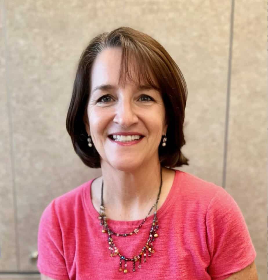 A smiling woman named Nancy in a pink shirt.