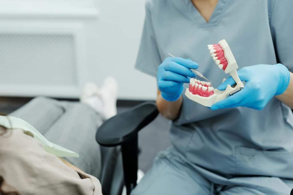 A dentist explaining dental implants to a patient while showcasing a model tooth.