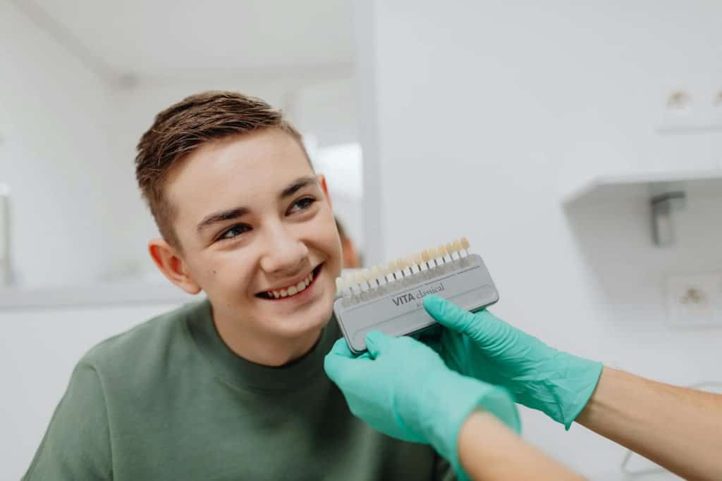 A young man is getting his teeth cleaned by a dentist, preparing for veneers.