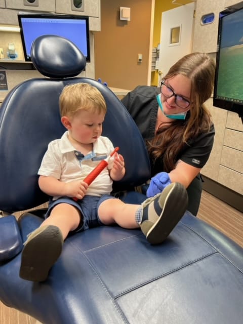 A young boy undergoing restorative dentistry while sitting in a dentist's chair.