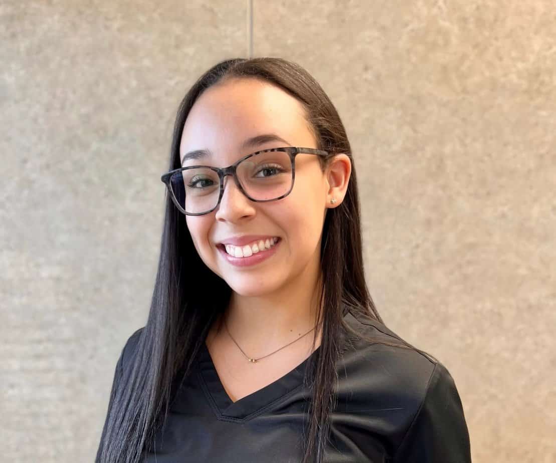 A smiling young woman wearing glasses and a black shirt.